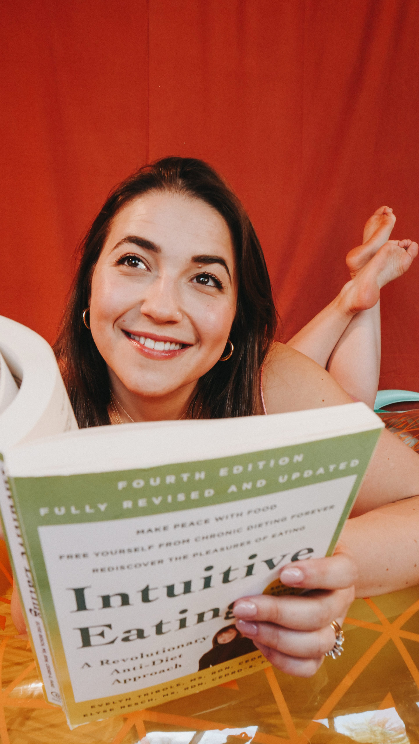 This is a picture of Alexandra thoughtfully reading Intuitive Eating by Elise Resch and Evelyn Tribole. She is getting ready to have a "Hot Girl Summer" exactly as she is, no changes necessary.